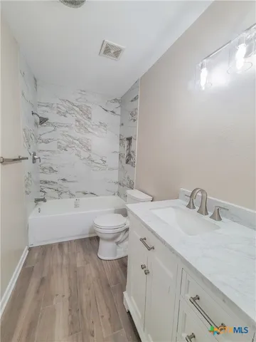 a bathroom with a granite countertop sink a toilet a mirror and bathtub