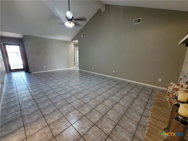 an empty room with windows and ceiling fan
