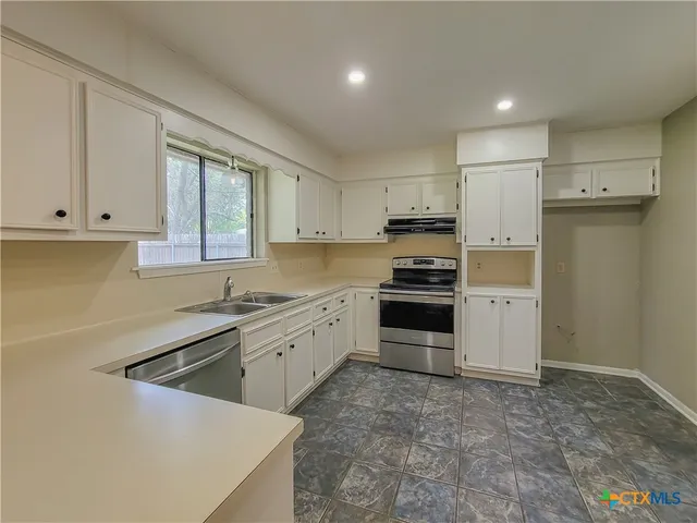 a kitchen with granite countertop white cabinets and stainless steel appliances