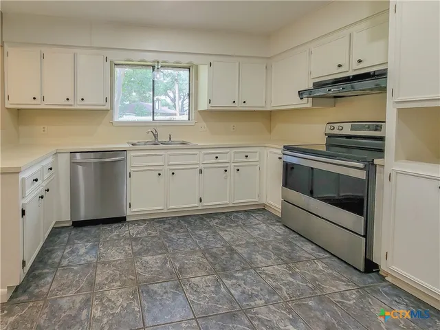 a kitchen with cabinets appliances and a window