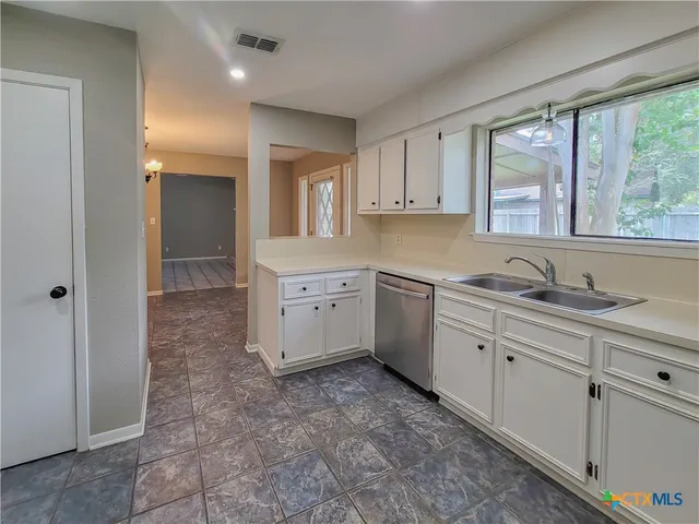a large white kitchen with a sink window and cabinets