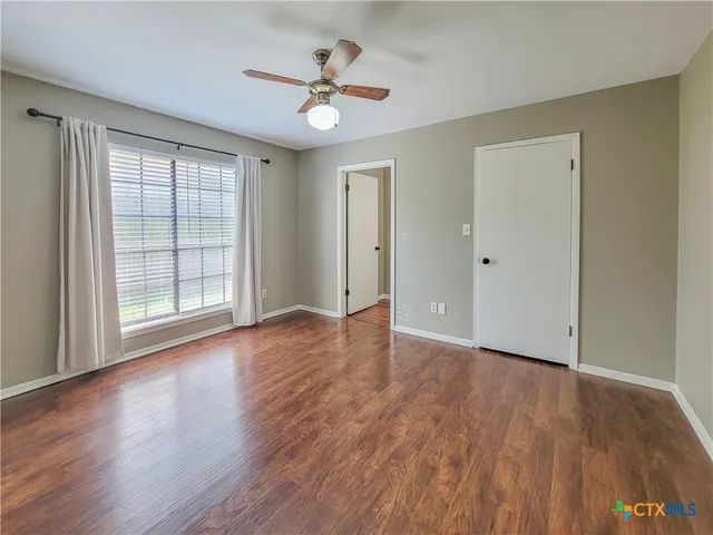 a view of an empty room with wooden floor and a window