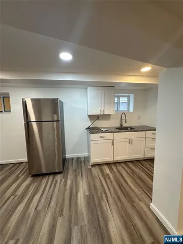 a kitchen with a sink a refrigerator and white cabinets