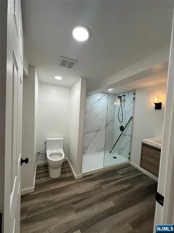 a view of a hallway with wooden floor and a toilet