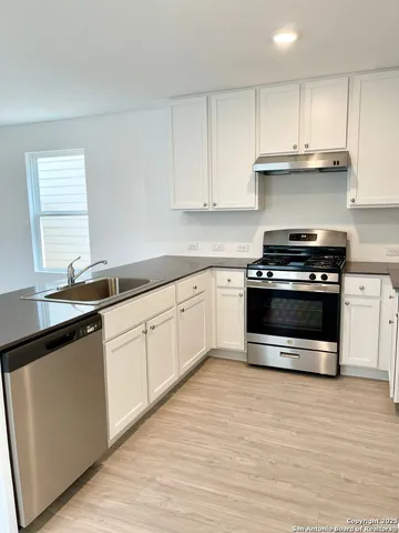 a kitchen with granite countertop white cabinets and appliances