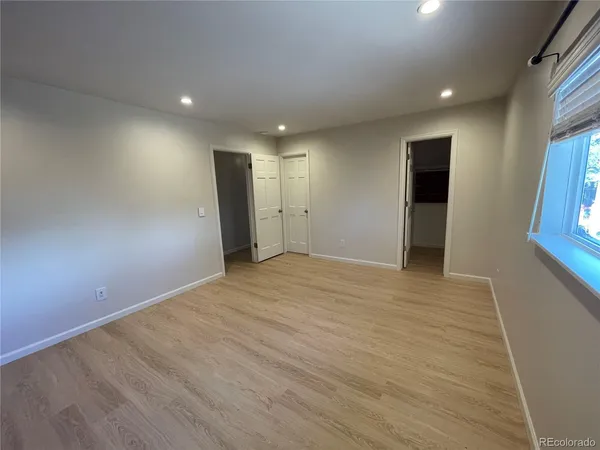 an empty room with wooden floor and windows