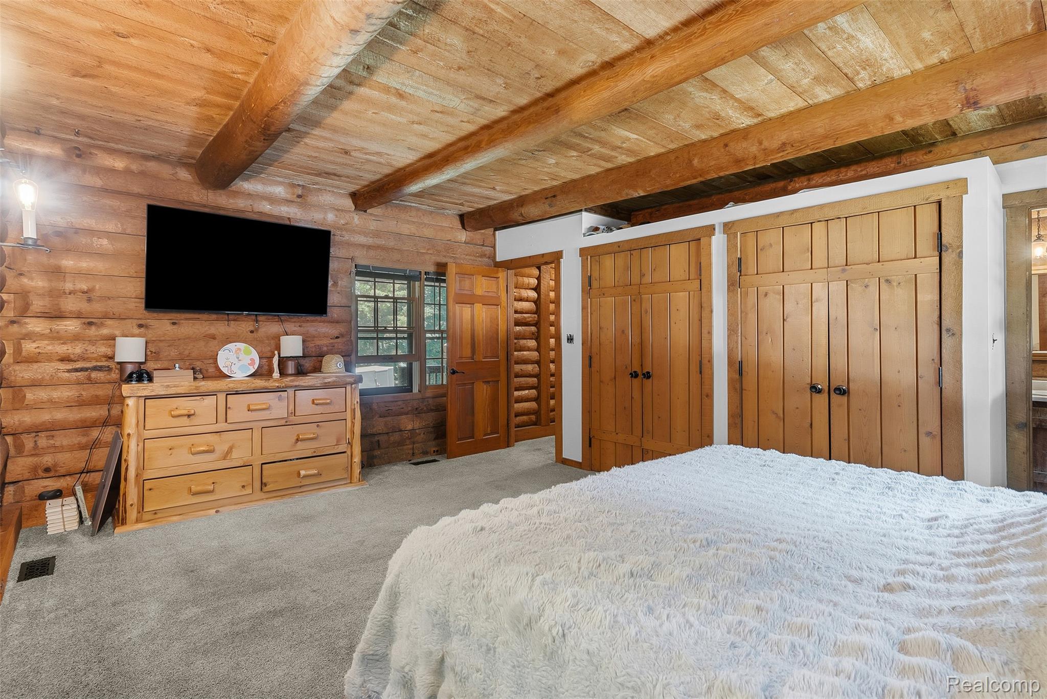 3656 Stanley Road Columbiaville, MI 48421 - Photo 21 of 65 Bedroom featuring log walls, wood plank ceiling with exposed beams, and light gray carpet