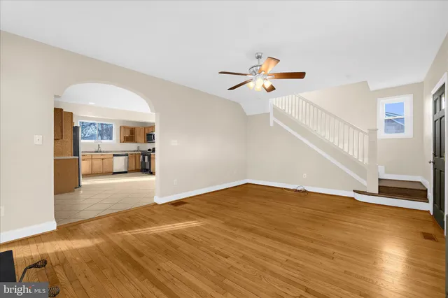 a view of a hallway with wooden floor and a kitchen