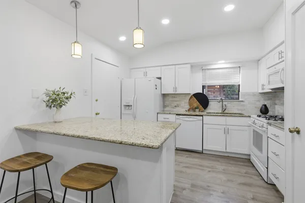 a kitchen with stainless steel appliances granite countertop a sink a stove a refrigerator a center island and chairs