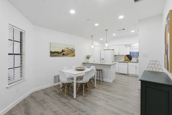 a kitchen with a dining table chairs stainless steel appliances and cabinets