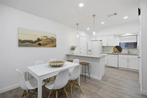 a kitchen with a dining table cabinets appliances and wooden floor
