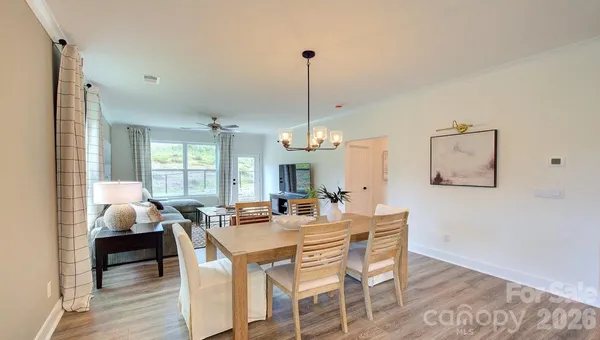a dining room with wooden floor a chandelier a wooden table and chairs