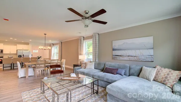 a living room with furniture kitchen view and a chandelier