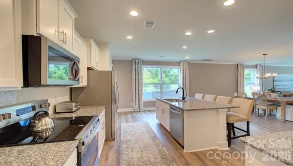 a living room with granite countertop furniture a rug kitchen view and a large window