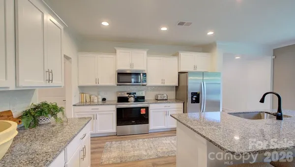 a kitchen with stainless steel appliances granite countertop a sink a stove and a refrigerator