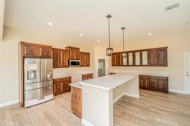 a kitchen with stainless steel appliances kitchen island wooden cabinets and wooden floor