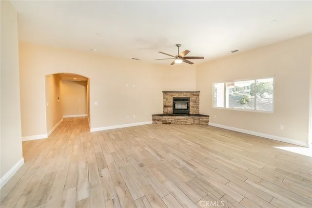 a view of empty room with a fireplace and wooden floor