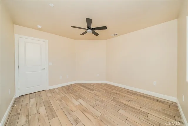 an empty room with wooden floor chandelier fan and windows