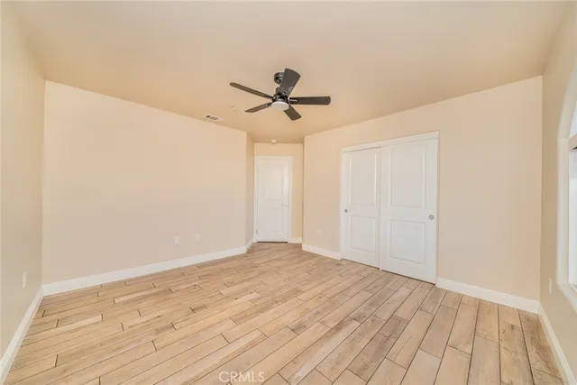 a view of a room with wooden floor fan and windows