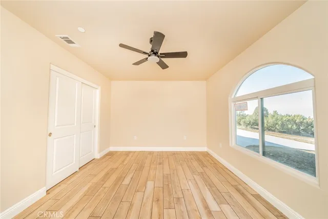 a view of a room with wooden floor and a ceiling fan
