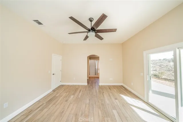 a view of a room with wooden floor and a ceiling fan