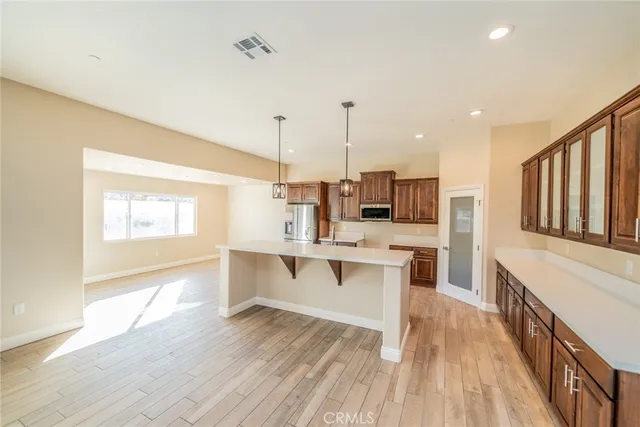 a open kitchen with stainless steel appliances kitchen island granite countertop a stove a sink and white cabinets with wooden floor