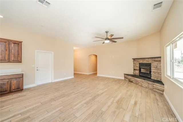 an empty room with wooden floor fireplace and windows