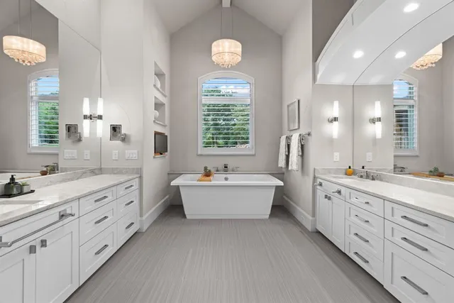 a spacious bathroom with double vanity a mirror a bathtub and a window