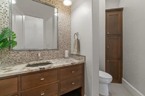 a bathroom with a granite countertop sink toilet and mirror