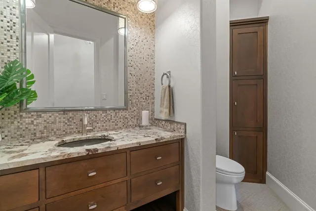 a bathroom with a granite countertop sink toilet and mirror