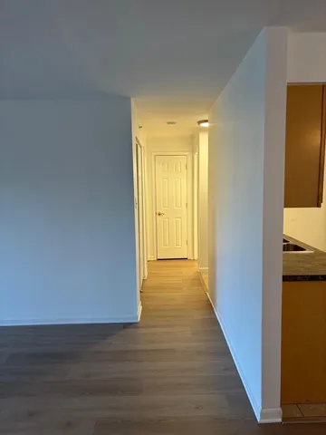 a view of a hallway with wooden floor and a bathroom