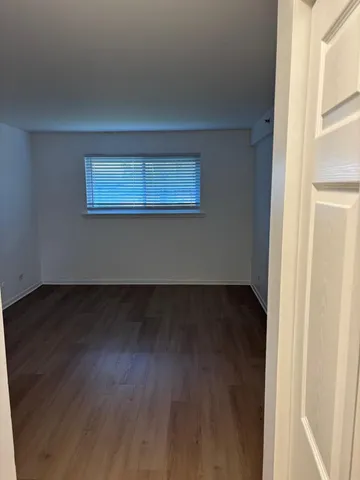 a view of a room that has wooden floor and a window