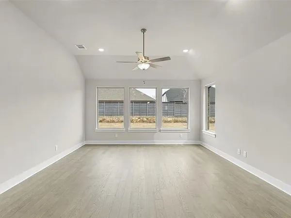 an empty room with wooden floor and windows