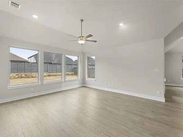 a view of an empty room with a window and wooden floor