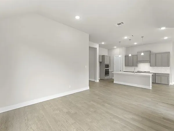 a view of an empty room and kitchen view