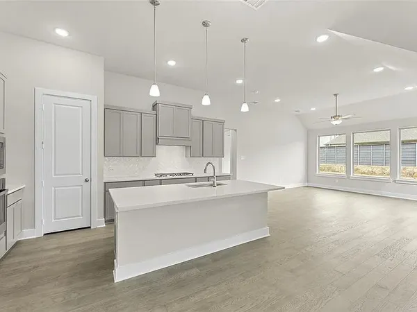 a large white kitchen with a large window a oven and a kitchen island