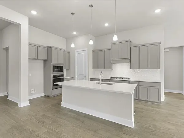 a large white kitchen with kitchen island a sink stainless steel appliances and cabinets