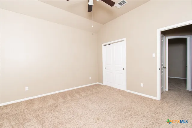 an empty room with a ceiling fan and carpet