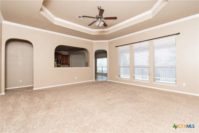 an empty room with windows and ceiling fan