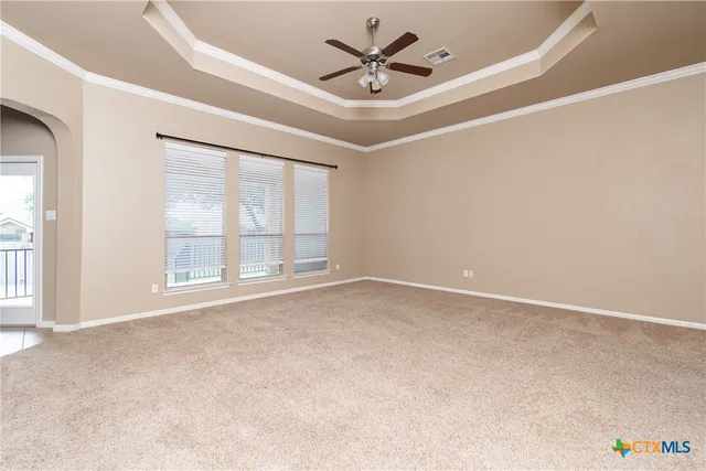 an empty room with windows and ceiling fan