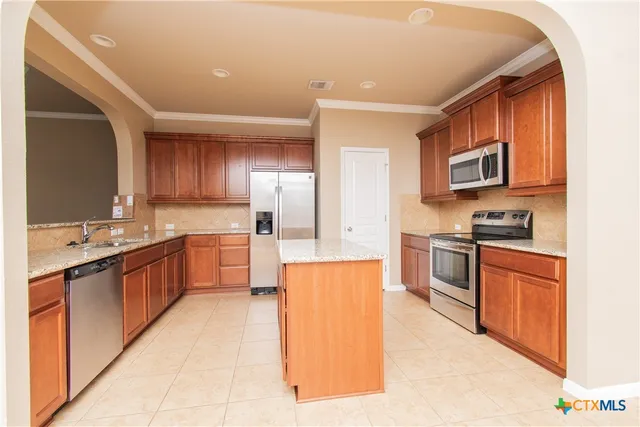 a large kitchen with stainless steel appliances wooden cabinets a stove and a refrigerator