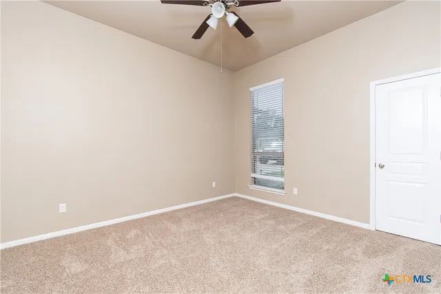 an empty room with a ceiling fan and carpet