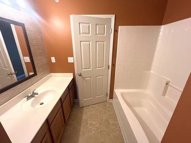 a bathroom with a tub sink and mirror