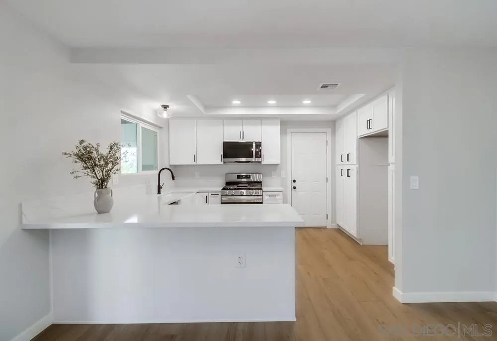8174 Sunset Road Lakeside, CA 92040 - Photo 9 of 46 a view of a kitchen with kitchen island a sink wooden floor and stainless steel appliances