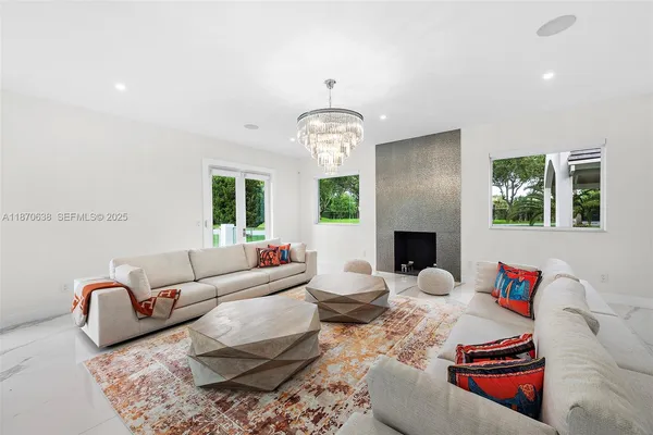 a living room with furniture a fireplace and a chandelier