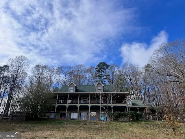 a view of a house with a large window and a yard with trees