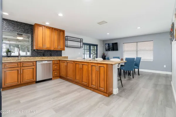 a kitchen with stainless steel appliances granite countertop wooden cabinets a sink a stove a dining table and chairs