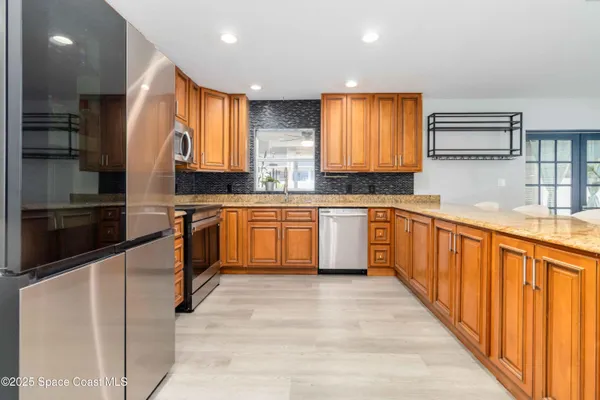 a kitchen with stainless steel appliances granite countertop wooden cabinets a sink dishwasher a stove and a refrigerator