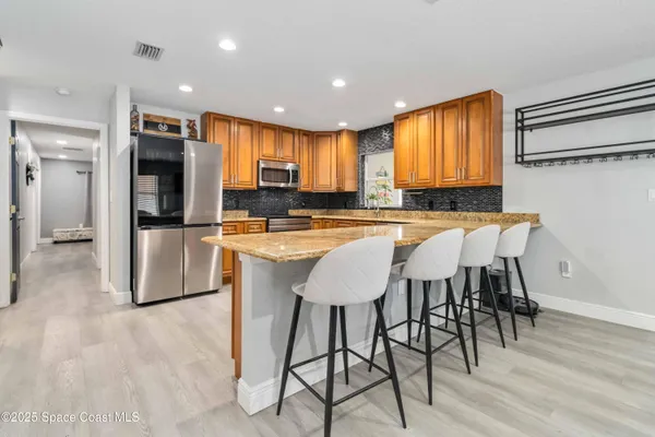 a kitchen with stainless steel appliances granite countertop a table chairs sink and cabinets