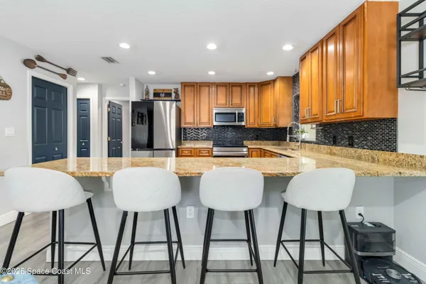 a kitchen with stainless steel appliances kitchen island granite countertop a dining table chairs and a sink